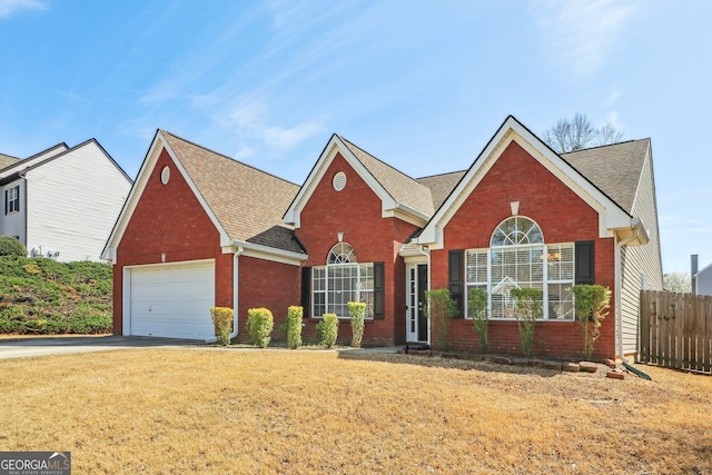 traditional-style house featuring brick siding, an attached garage, a front lawn, and fence