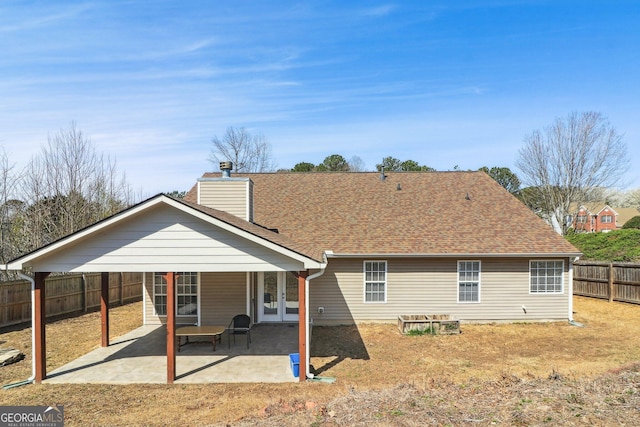 back of house with a patio area, a chimney, a fenced backyard, and roof with shingles