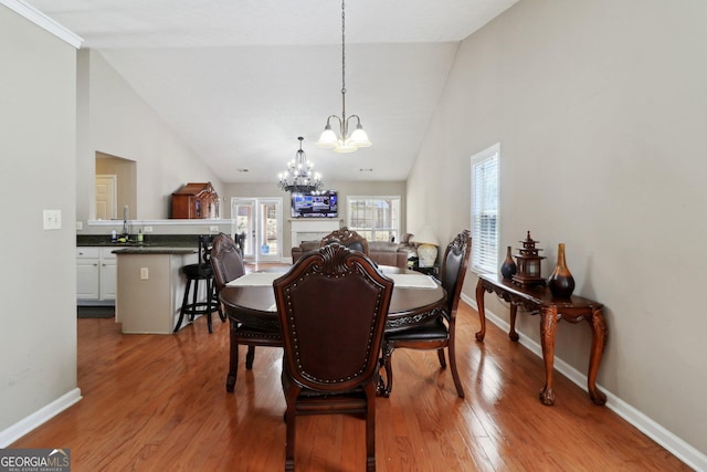 dining room featuring high vaulted ceiling, baseboards, wood-type flooring, and a chandelier