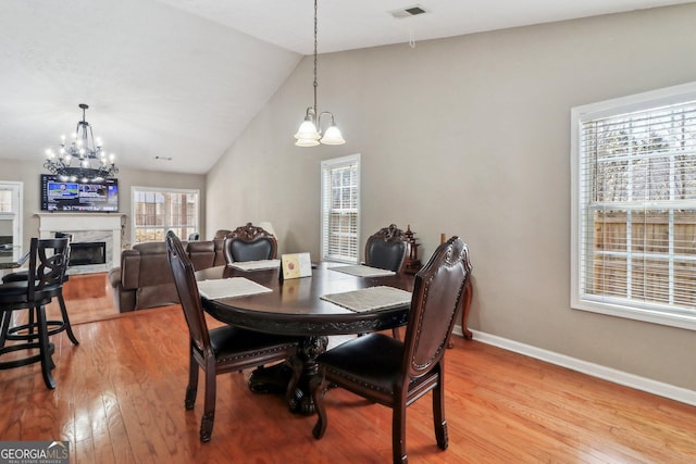 dining space with a chandelier, visible vents, light wood-style flooring, and a fireplace