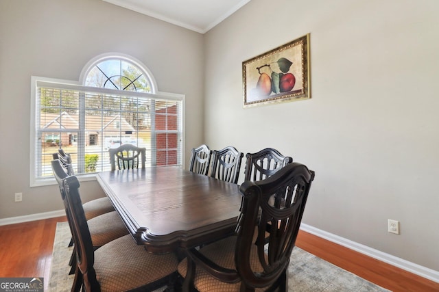 dining room featuring wood finished floors, baseboards, and ornamental molding