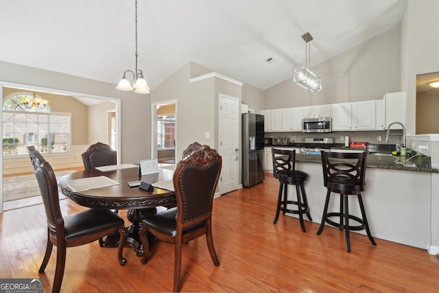 dining room featuring high vaulted ceiling, a chandelier, and light wood finished floors