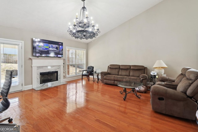 living area with a wealth of natural light, vaulted ceiling, a high end fireplace, and wood finished floors