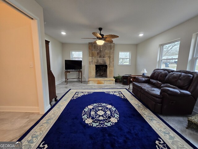 living area featuring baseboards, a healthy amount of sunlight, and a fireplace