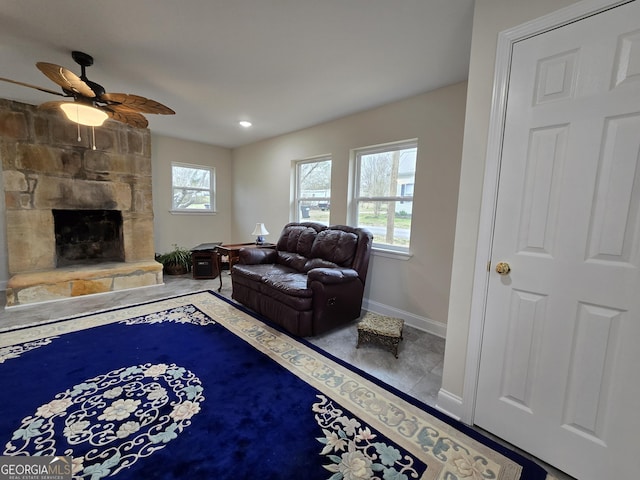 living area with a ceiling fan, a fireplace, and baseboards