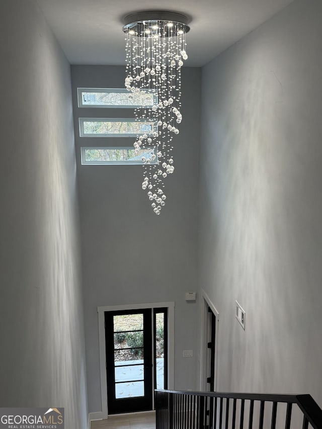 foyer featuring visible vents, a healthy amount of sunlight, a chandelier, and a towering ceiling