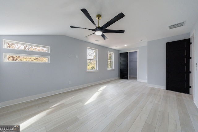 unfurnished bedroom featuring lofted ceiling, multiple windows, light wood-style floors, and visible vents