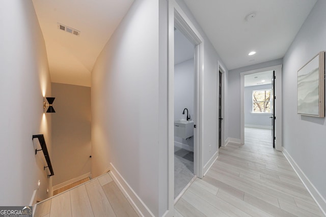 corridor with light wood finished floors, visible vents, baseboards, an upstairs landing, and recessed lighting