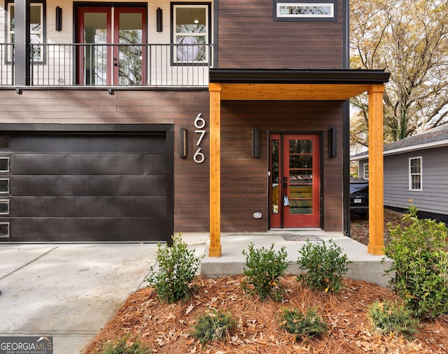 view of exterior entry featuring a garage, a porch, and concrete driveway