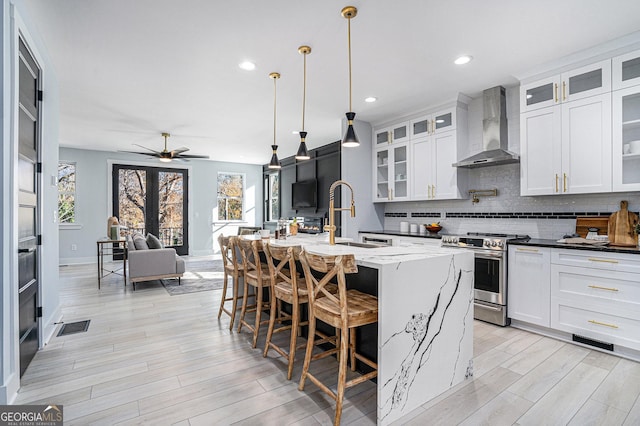 kitchen featuring a sink, tasteful backsplash, open floor plan, stainless steel electric range, and wall chimney exhaust hood