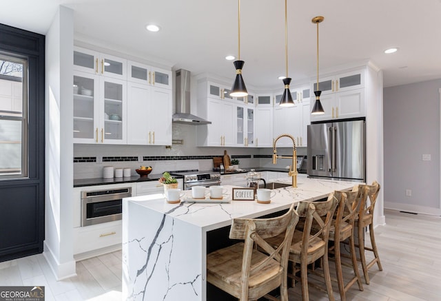 kitchen with white cabinetry, tasteful backsplash, appliances with stainless steel finishes, and wall chimney range hood