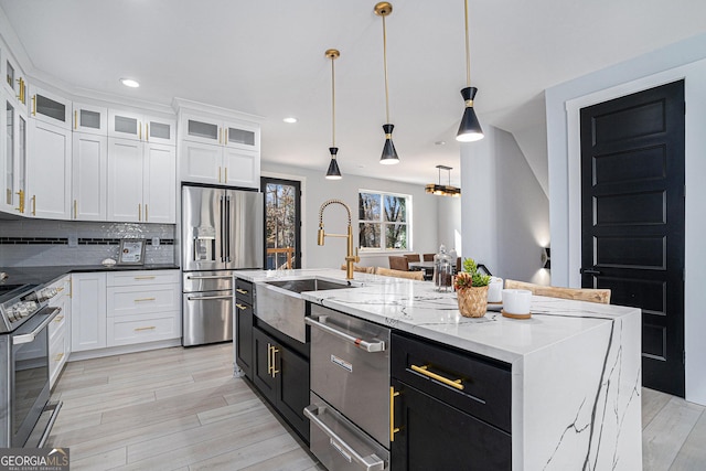 kitchen with a warming drawer, a sink, tasteful backsplash, stainless steel appliances, and white cabinets