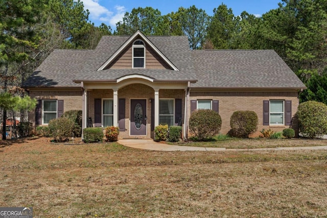 view of front of house with brick siding, a shingled roof, and a front lawn