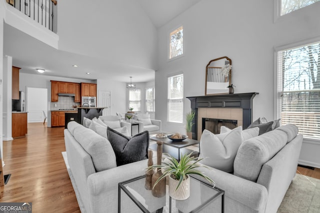 living room with baseboards, light wood finished floors, a high ceiling, recessed lighting, and a fireplace