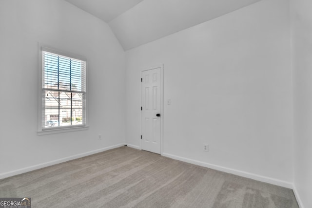 carpeted empty room with baseboards and vaulted ceiling