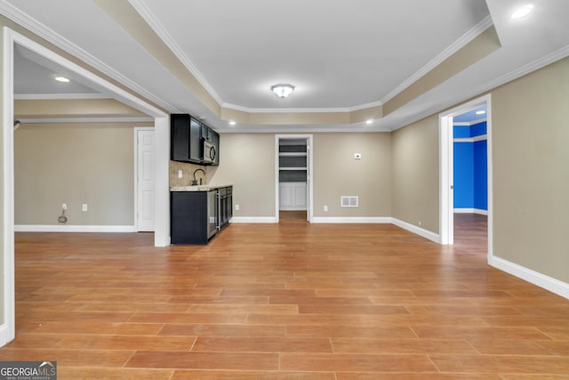 1654 Summersweet Ln, Dacula, GA 30019 - unfurnished living room with a tray ceiling, light wood finished floors, bar with sink, ornamental molding, and recessed lighting
