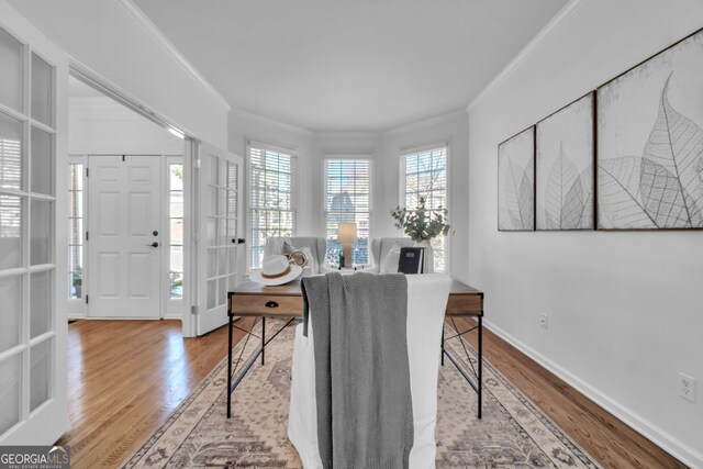 office with crown molding, a decorative wall, and wood finished floors