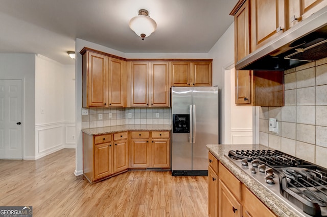 1654 Summersweet Ln, Dacula, GA 30019 - kitchen with appliances with stainless steel finishes, under cabinet range hood, decorative backsplash, light wood-style floors, and light stone countertops