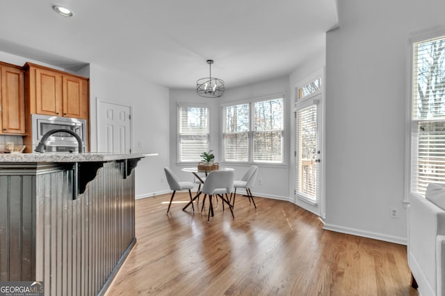 1654 Summersweet Ln, Dacula, GA 30019 - kitchen with a chandelier, a breakfast bar area, light wood-style floors, stainless steel microwave, and brown cabinets