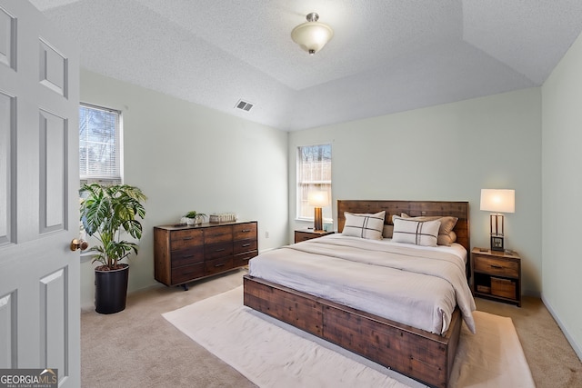 bedroom with a textured ceiling, multiple windows, visible vents, and light carpet