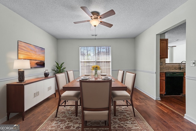 dining room with visible vents, dark wood-type flooring, a ceiling fan, a textured ceiling, and baseboards