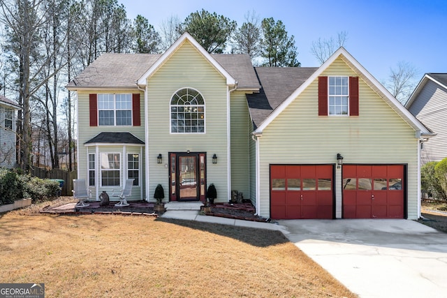 traditional-style house with concrete driveway, a garage, and a front yard