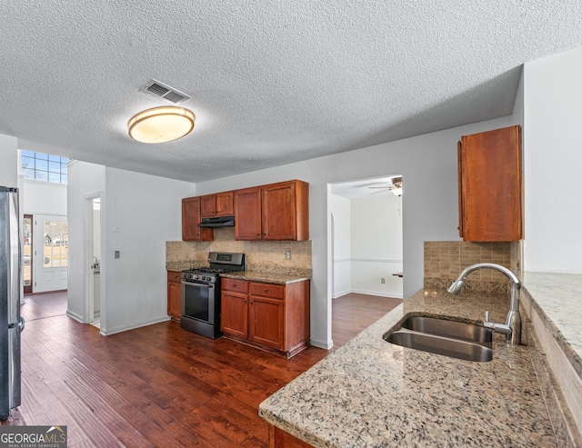 kitchen with visible vents, dark wood finished floors, a sink, under cabinet range hood, and appliances with stainless steel finishes