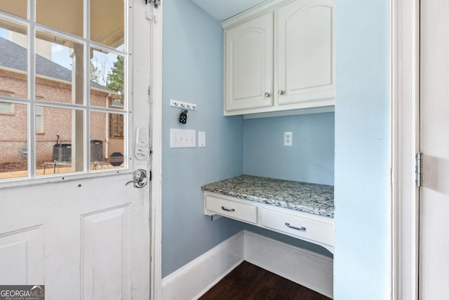 mudroom with built in desk, baseboards, and dark wood-style flooring