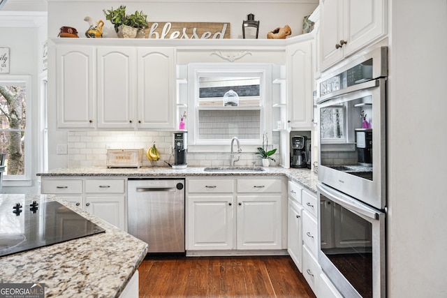 kitchen with backsplash, dark wood-style floors, white cabinets, stainless steel appliances, and a sink