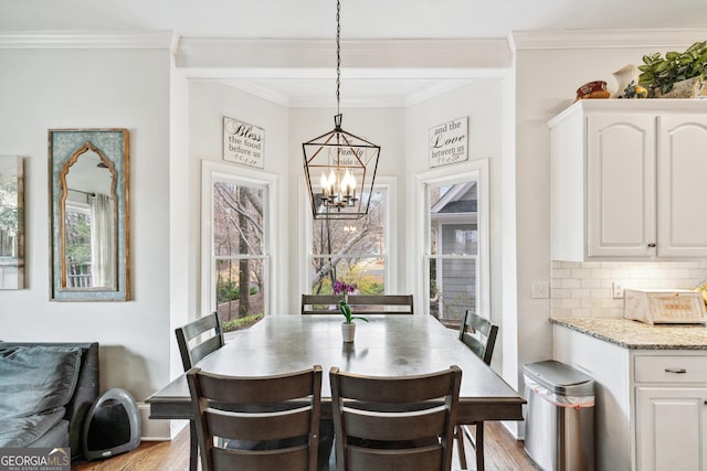 dining room with a notable chandelier, light wood-style floors, and crown molding