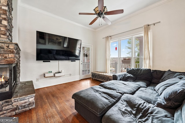 living room with a stone fireplace, wood finished floors, a ceiling fan, and ornamental molding