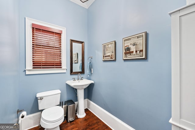 half bathroom with toilet, baseboards, and wood finished floors