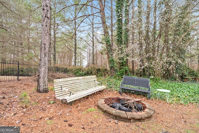 surrounding community with a fire pit and fence