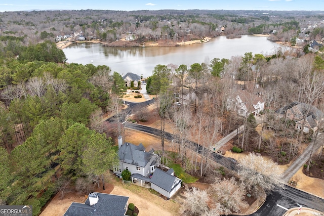 drone / aerial view with a wooded view and a water view