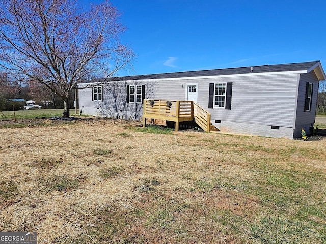 rear view of house with crawl space, a wooden deck, and a yard