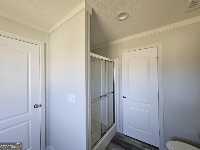 full bath with visible vents, a textured ceiling, a shower stall, and toilet