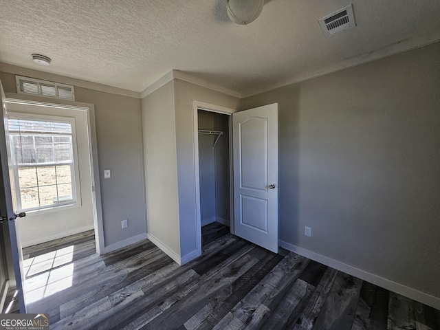 unfurnished bedroom featuring visible vents, dark wood-type flooring, and baseboards