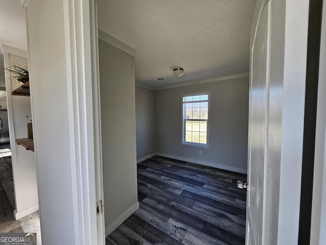 spare room featuring visible vents, ornamental molding, a textured ceiling, wood finished floors, and baseboards