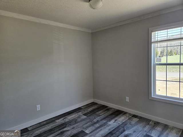 empty room with dark wood finished floors, a healthy amount of sunlight, baseboards, and a textured ceiling