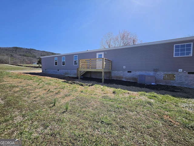 rear view of property featuring a deck, central AC unit, a lawn, and crawl space