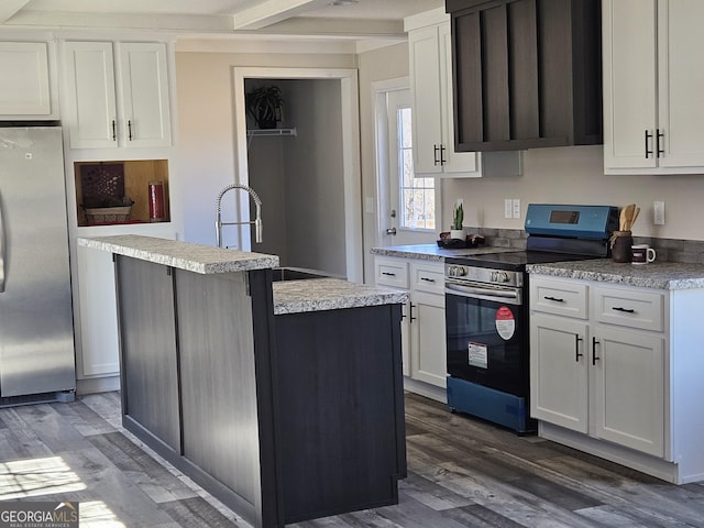 kitchen featuring white cabinetry, stainless steel appliances, an island with sink, and wood finished floors