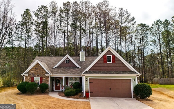 craftsman-style house with a chimney, concrete driveway, a front yard, and fence