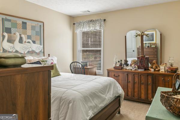 bedroom with visible vents and light carpet