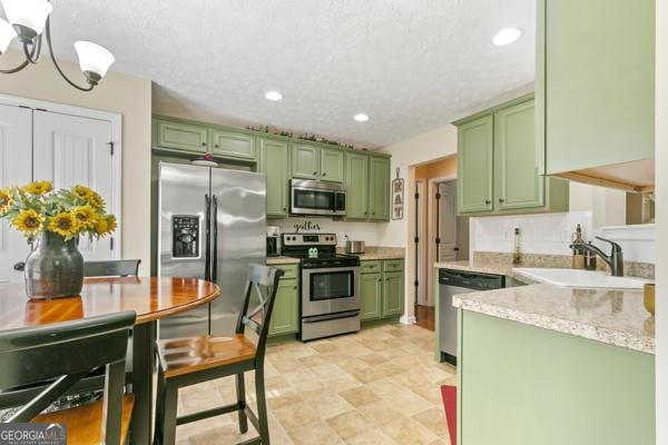 kitchen featuring green cabinetry, stainless steel appliances, recessed lighting, and a sink