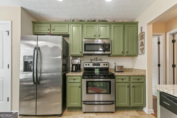 kitchen with decorative backsplash, light stone counters, green cabinetry, and stainless steel appliances