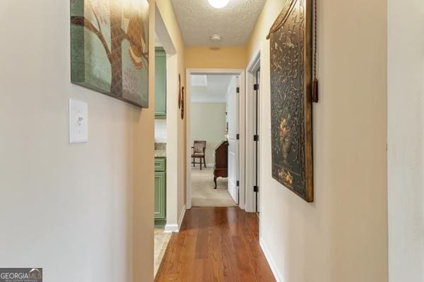 corridor featuring baseboards, a textured ceiling, and wood finished floors