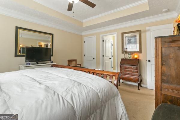 bedroom with carpet flooring, ceiling fan, a tray ceiling, and ornamental molding