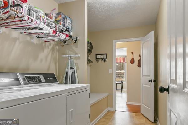 laundry room featuring washer and dryer, laundry area, baseboards, and a textured ceiling