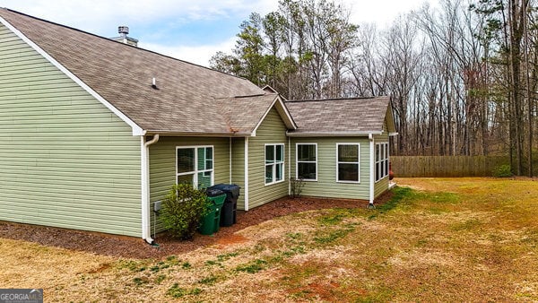 back of house with a yard and roof with shingles