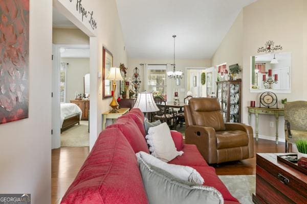 living area featuring high vaulted ceiling, wood finished floors, and a chandelier